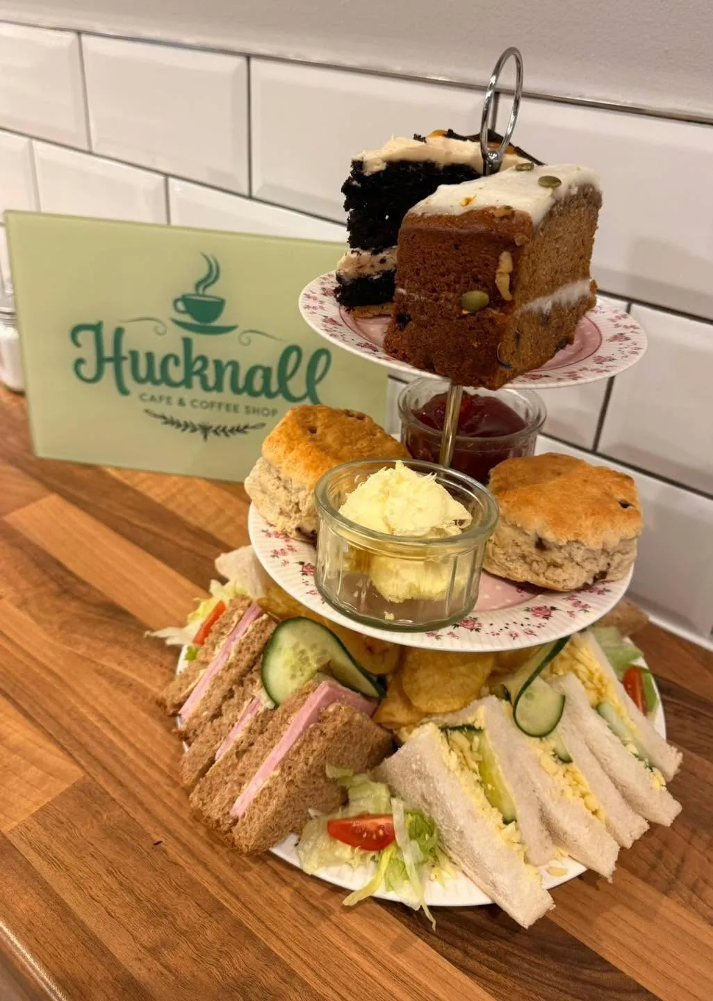 Afternoon tea stand with sandwiches, scones, jam, cream and slices of cake