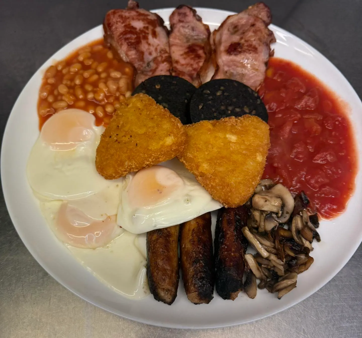 Loaded full English breakfast with hash browns, black pudding, sausages, bacon, eggs, beans and mushrooms