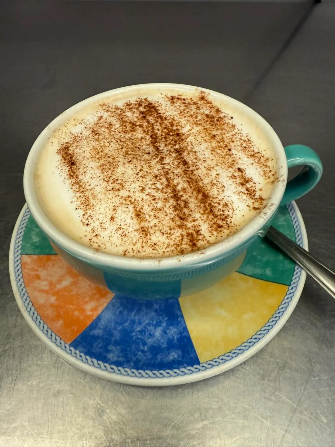 Freshly made cappuccino with chocolate dusting in a colourful cup