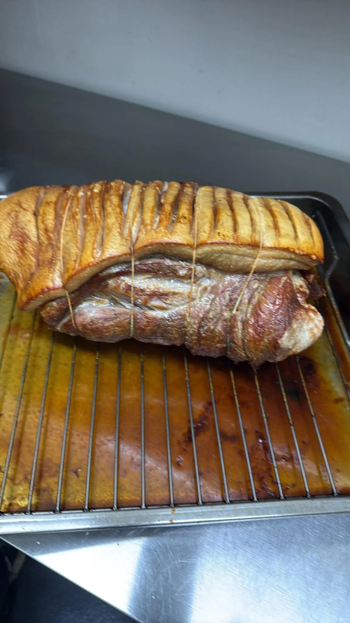 Whole roast pork shoulder with golden crackling on a roasting rack